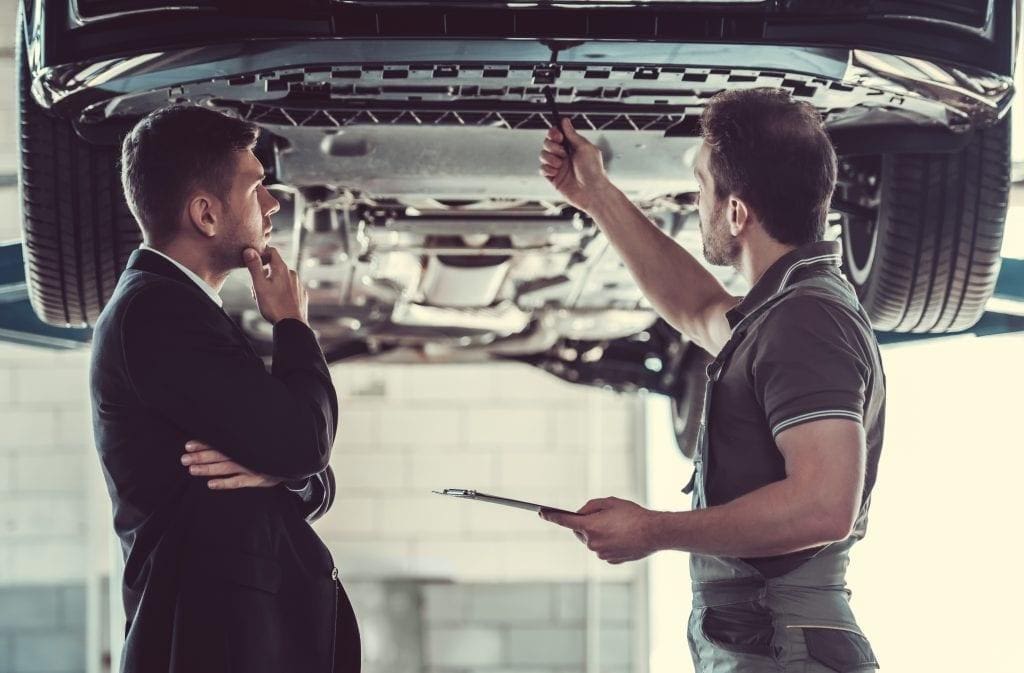 mechanic inspects car with customer