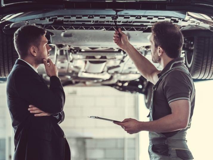 mechanic inspects car with customer