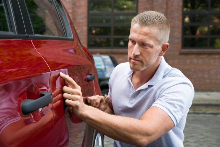 Person closely inspecting a car