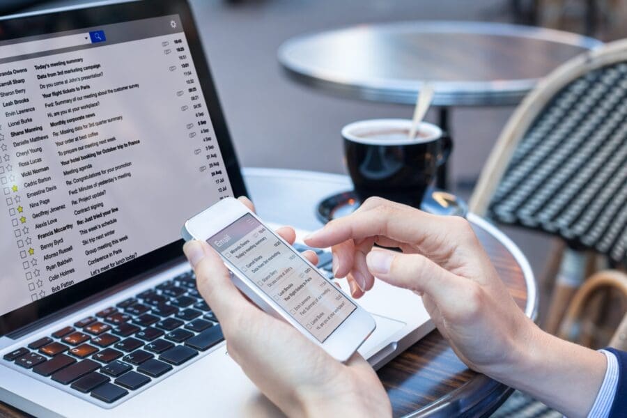 Person texting on phone in front of open laptop
