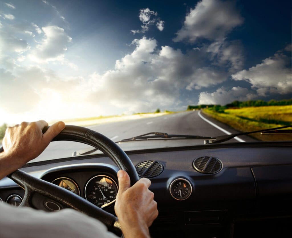 Hands on the wheel of a car driving down the road