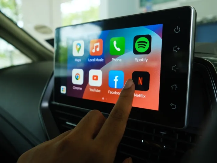Driver selecting an app on the vehicle's infotainment screen