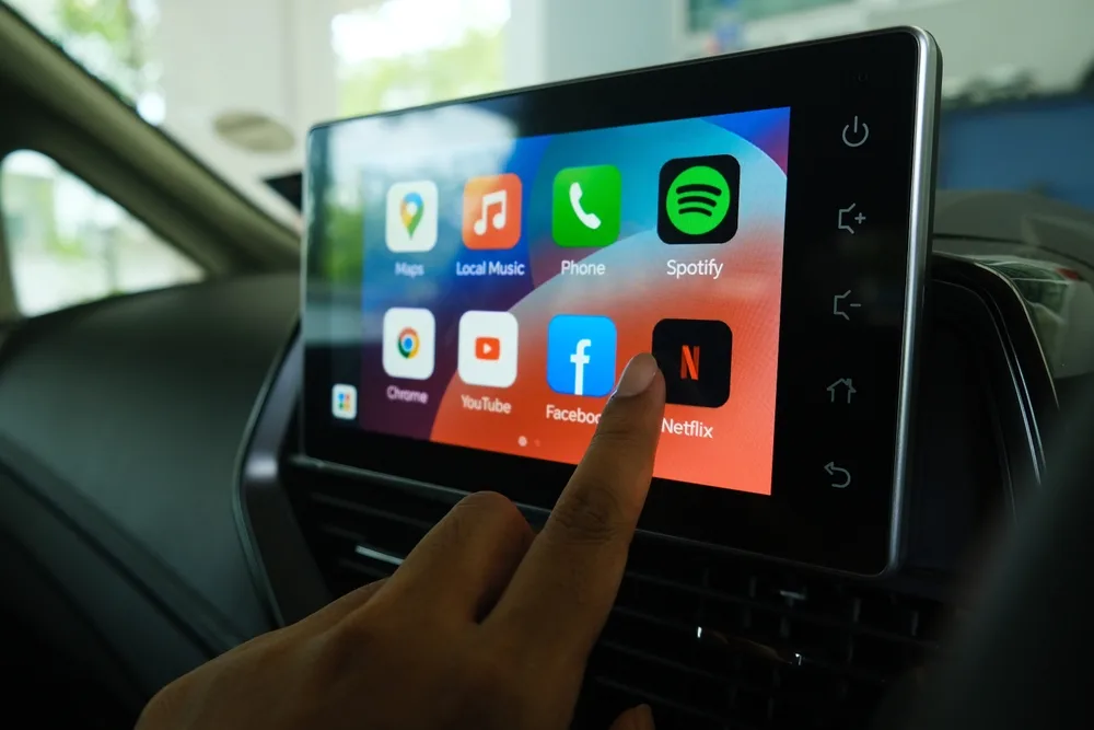 Driver selecting an app on the vehicle's infotainment screen
