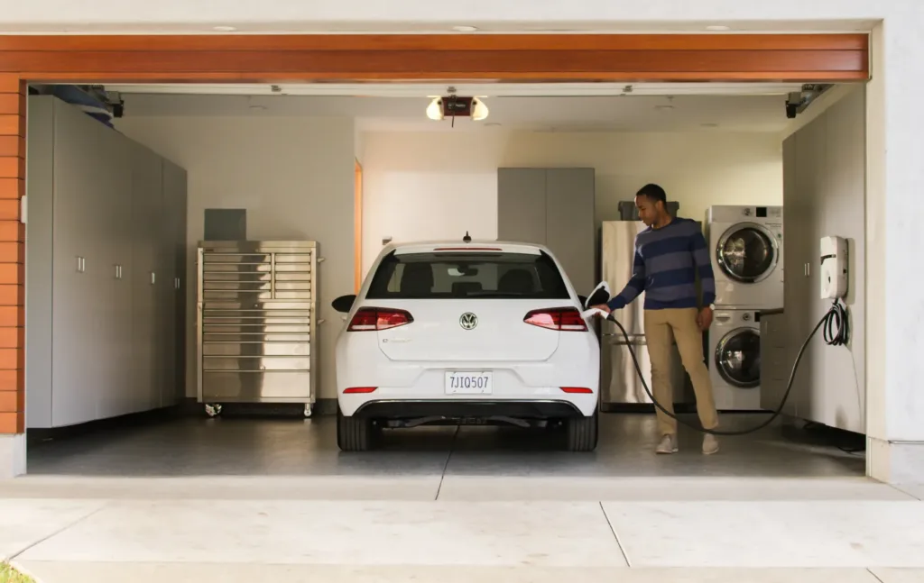 2017 Volkswagen e-Golf parked in garage with man connecting charger